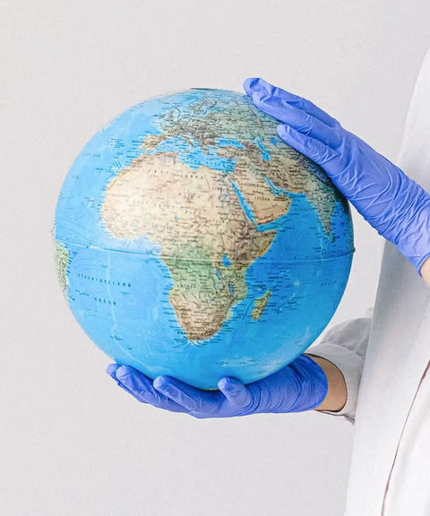 Hands wearing blue gloves holding a globe, symbolizing global reach, responsibility, and leadership in the marketplace